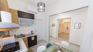 Eine kompakte Küche mit Mikrowelle, Herd und Spüle. Es gibt einen Essbereich mit Tisch und Stühlen sowie einen kleinen Kühlschrank.