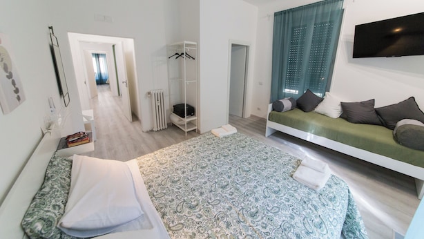 Ein modernes Schlafzimmer mit Bett, Sofa, Fernseher und begehbarem Kleiderschrank.