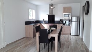 Eine moderne Küche mit Essbereich, ausgestattet mit einer Kochinsel, schwarzen Stühlen und einem Holztisch.