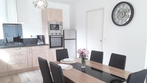 Eine moderne Küche mit Essbereich, ausgestattet mit einem Holztisch, schwarzen Stühlen und einer kleinen Vase mit Blumen.