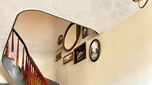 A staircase with wooden balusters and a handrail, leading to a landing with a wall decorated with framed pictures and a mirror. - Superb 4-bedroom historical house in Fredericktown (Fredericktown)
