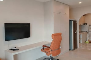 A modern living room with a flat-screen TV, a swivel chair, and a built-in cabinet. - View Talay Studio (Pattaya)
