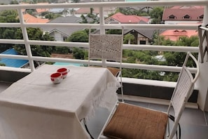 A balcony with a table, chairs, and a view of houses and trees. - View Talay Studio (Pattaya)