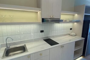 A modern kitchen with a stainless steel sink, white cabinets, and a black countertop. - View Talay Studio (Pattaya)