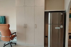 A kitchenette with a stainless steel refrigerator, a chair, and cabinets. - View Talay Studio (Pattaya)