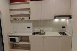 A kitchen with white cabinets, a microwave, a sink, and a stove. - View Talay Studio (Pattaya)