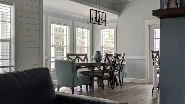 Un espace repas comprenant une table ronde, plusieurs chaises et un lustre.