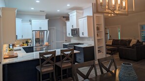 Une cuisine moderne avec des meubles blancs, des appareils en acier inoxydable et un îlot central doté de tabourets de bar.