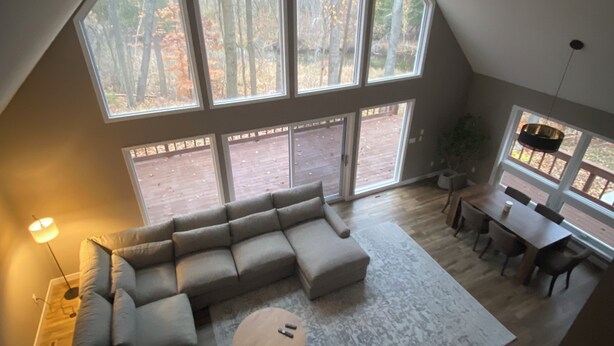 A spacious loft with a large skylight, a sectional sofa, a dining table, and a view of the surrounding forest. - Looking for a perfect getaway? (Stanwood)