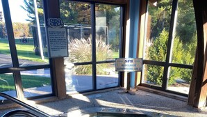 A hot tub with a metal ladder, surrounded by a wooden deck and a glass enclosure with a view of a golf course. - Looking for a perfect getaway? (Stanwood)
