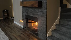 A modern living room with a fireplace, wooden flooring, and a staircase. - Looking for a perfect getaway? (Stanwood)