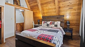 A bedroom with a wooden ceiling, a bed with a plaid bedspread, two bedside tables with lamps, and a wardrobe with a mirror. - New Listing! In Town, Ski-In, Ski-Out! "Claim Jumper A-Frame 6" Pet Friendly, (Red River)