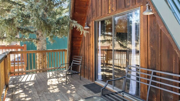 A wooden deck with a glass door leading to an outdoor seating area. - New Listing! In Town, Ski-In, Ski-Out! "Claim Jumper A-Frame 6" Pet Friendly, (Red River)