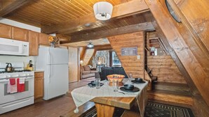 A cozy attic-style kitchen with wooden beams, a white stove, and a dining table set for four. - New Listing! In Town, Ski-In, Ski-Out! "Claim Jumper A-Frame 6" Pet Friendly, (Red River)