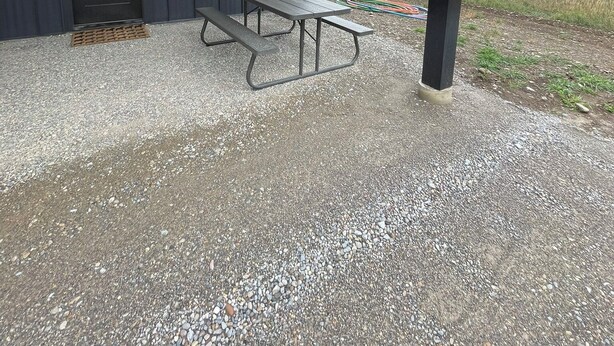 Een zwart gebouw met een picknicktafel en een deur.
