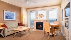 A living room with a fireplace, a sofa, a coffee table, and a dining area. - Seaside Beachfront, Spring Break, beautiful, welcoming Condo. STEPS TO THE BEACH (Seaside)