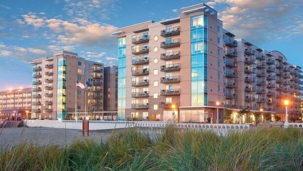 A modern multi-story residential building with balconies, large windows, and a waterfront view. - Seaside Beachfront, Spring Break, beautiful, welcoming Condo. STEPS TO THE BEACH (Seaside)