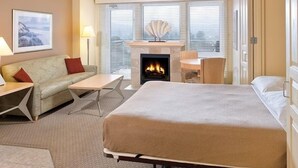A hotel room with a bed, a sofa, a table, and a fireplace. - Seaside Beachfront, Spring Break, beautiful, welcoming Condo. STEPS TO THE BEACH (Seaside)