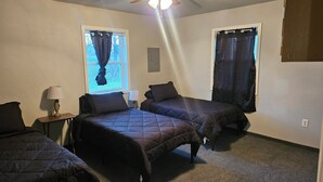 Une chambre avec deux lits, un ventilateur de plafond et une fenêtre avec des rideaux.
