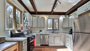 Une cuisine moderne avec des armoires blanches, des appareils en acier inoxydable et un plancher en bois.