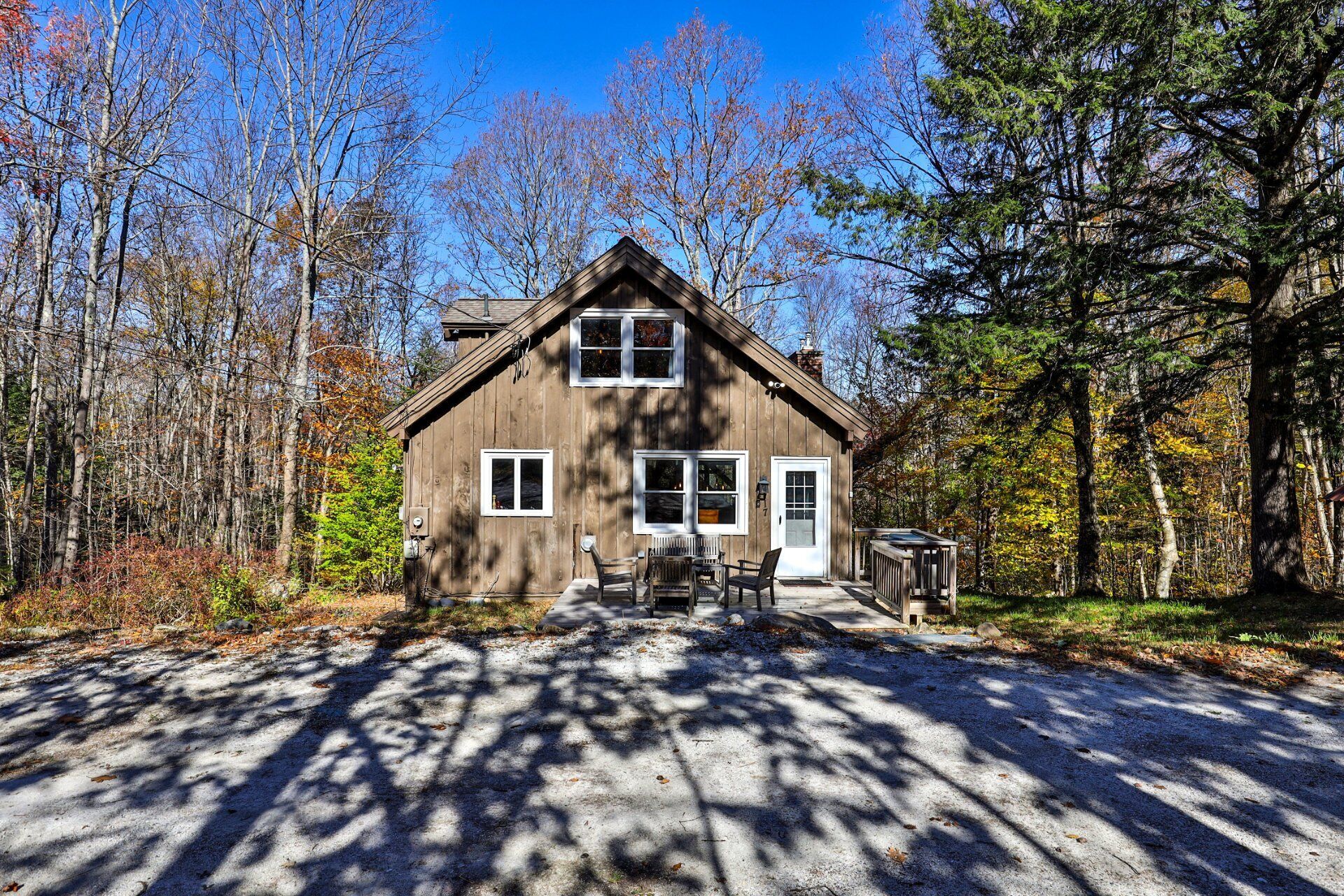 A wooden cabin with a front porch, surrounded by trees.
