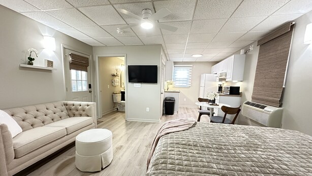 A modern, well-lit room with a large bed, a sofa, a small table, and a TV. - Cozy Studio Retreat W/ Pool Near Charlotte Airport (Gastonia)