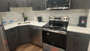 Una cocina moderna con armarios de madera oscura, electrodomésticos de acero inoxidable y encimera blanca.