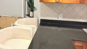 Una cocina con encimera negra, armarios de madera y una planta en maceta.