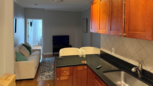 Una cocina moderna con armarios de madera, encimera negra y pileta de acero inoxidable.