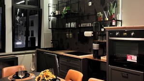 Et moderne køkken med spiseplads, i sort og hvid, med en hængende lampe og et indbygget ovn.