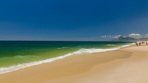 En la playa, playa de arena blanca, camastros y sombrillas 