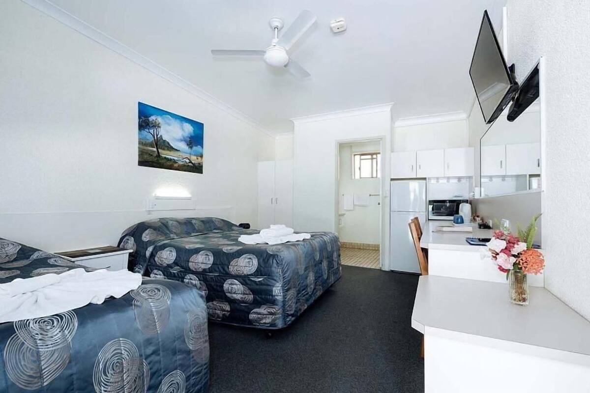 A room with two beds, a desk, a chair, a TV, and a painting on the wall.