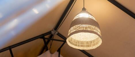 A hanging woven light fixture in a tent-like structure.