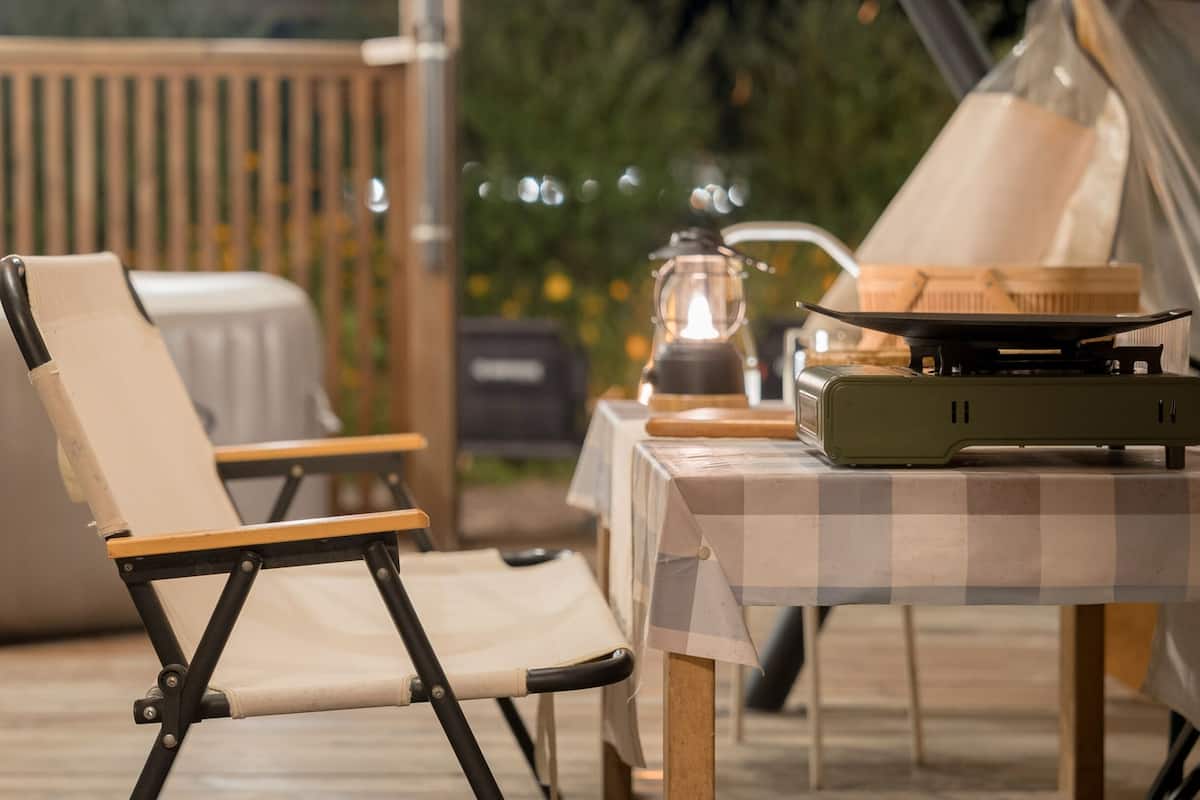 Een eethoek met een tafel voor twee, een draagbare grill en een lantaarn.