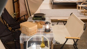 Un hébergement confortable en forme de tente, avec une table à carreaux, un panier en osier, une lanterne et une bouteille.