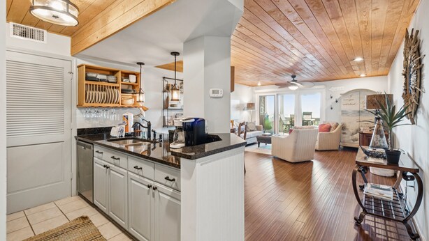 Een moderne keuken met houten balken in het plafond, een centraal eiland en een zithoek met een bank en salontafel.
