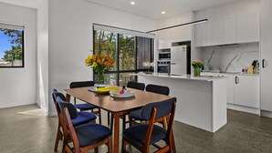 A modern kitchen with white cabinets, a marble backsplash, and a built-in oven. - Riverside Modern Abode with 2 Aircons and Parking (Auckland South)