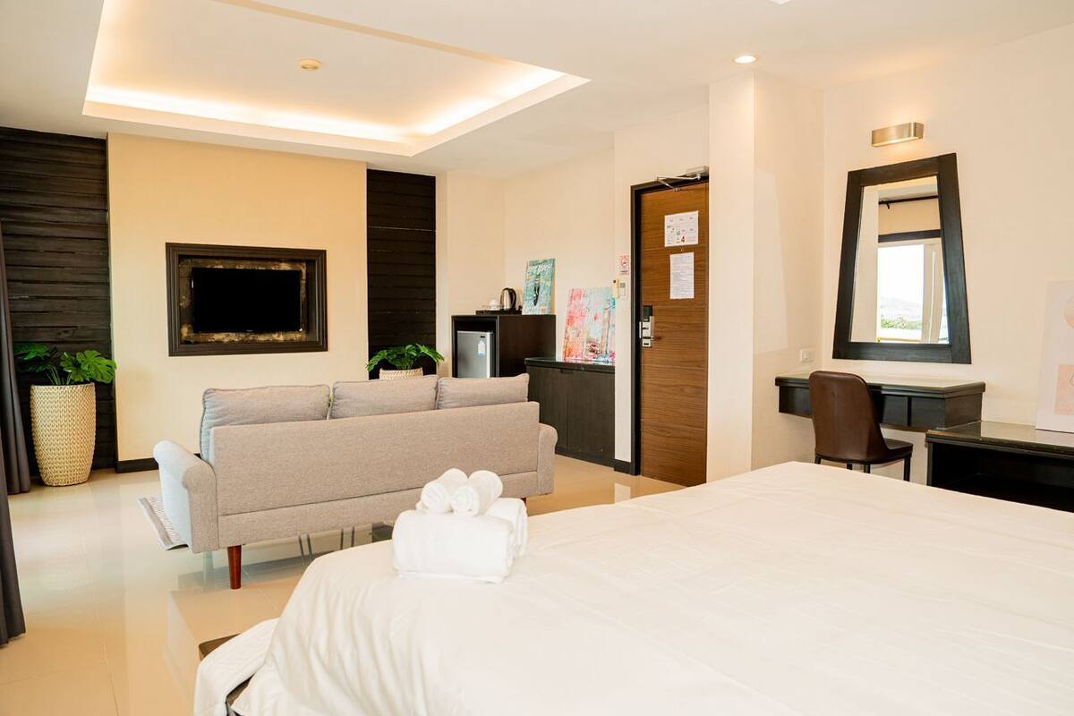 A hotel room with a bed, a sofa, a desk, and a mirror.