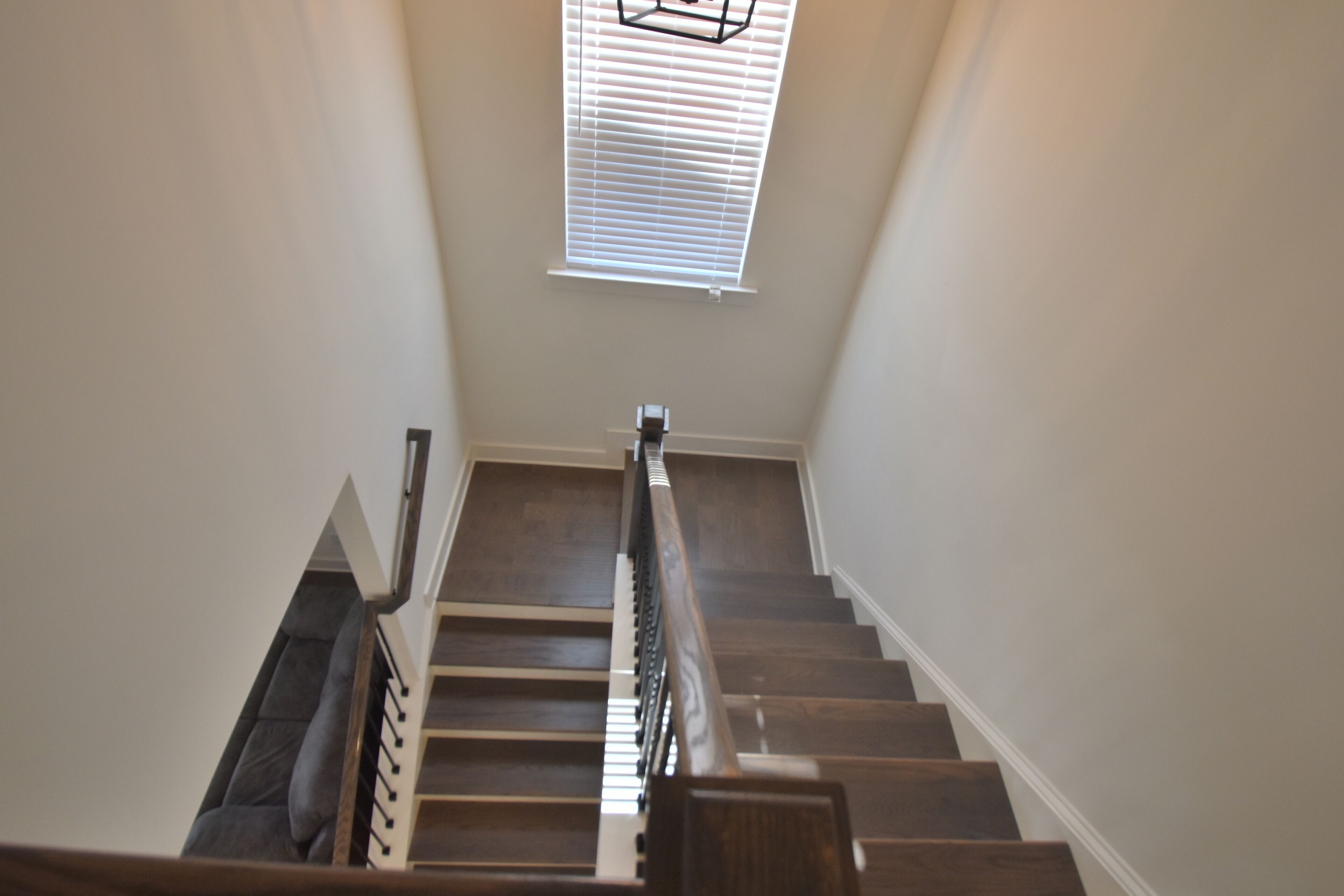 A staircase with wooden steps and a handrail, leading to a room with a ceiling window.