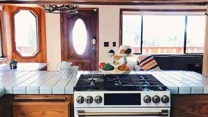 A kitchen with wooden cabinets, a stove, and a window with a view. - L'Après Chalet · Bear Mtn Views · Sleeps 6 · Pet-Friendly (Big Bear Lake)