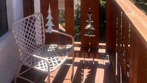 A balcony with a wooden railing, a white metal chair, and a wall-mounted light fixture. - L'Après Chalet · Bear Mtn Views · Sleeps 6 · Pet-Friendly (Big Bear Lake)