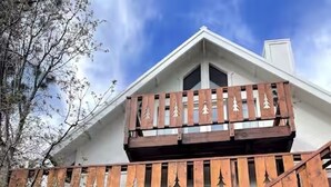 A wooden staircase with tree-shaped cutouts leading to a white building with a gabled roof. - L'Après Chalet · Bear Mtn Views · Sleeps 6 · Pet-Friendly (Big Bear Lake)