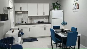 A modern kitchen with white cabinets, a white refrigerator, and a dining area with blue chairs and a table. - Blue Dream Sunrise "Your Journey, Our Passion" Cozy retreat in lovely Lakeland (Lakeland)