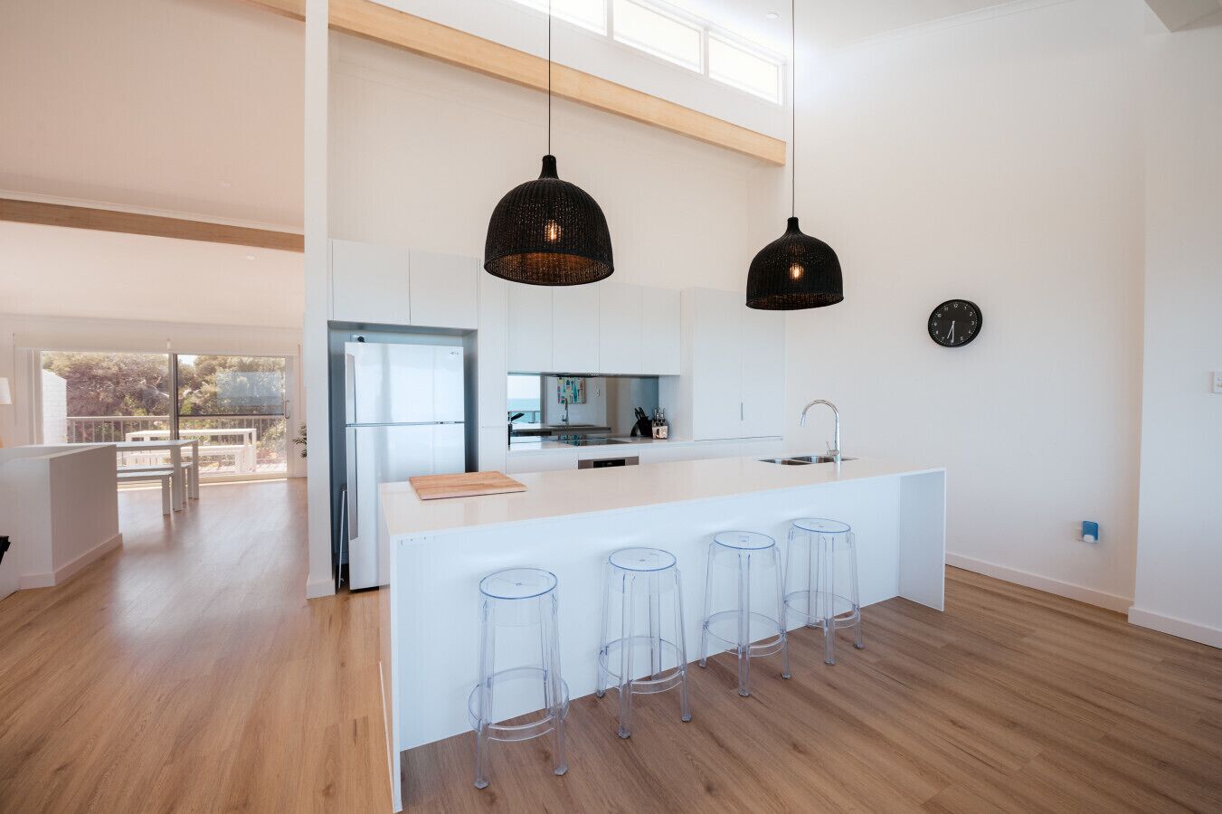 A modern kitchen with a large island, pendant lights, and a view to the outside.