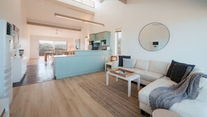 Um interior moderno com uma ilha central, um sofá, uma mesa de centro e um ventilador de teto.