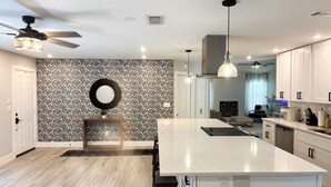 A modern kitchen with a large island, white cabinetry, a patterned backsplash, and a ceiling fan. - 3 Bedroom Sunny Cape Coral Escape, 3 blocks from Lee Health, no cleaning fee! (Cape Coral)