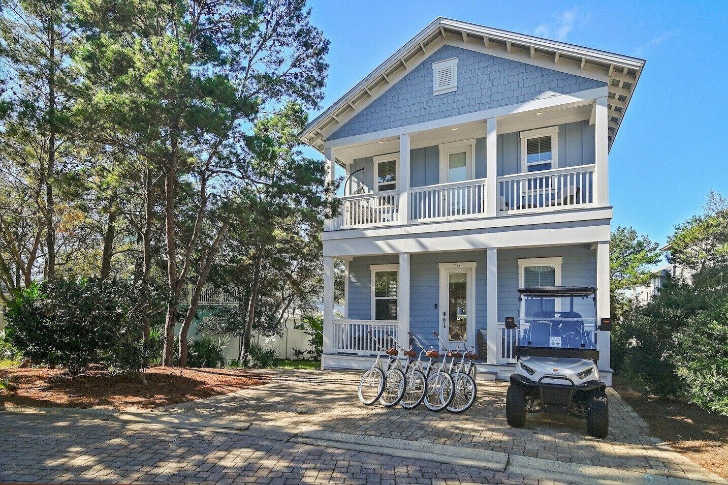 A two-story house with a porch, a covered front entrance, and a vehicle parked in front.