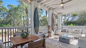 A covered outdoor patio with a wooden table, chairs, a sofa, and a ceiling fan.