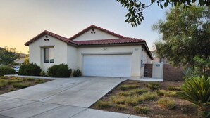 A single-story house with a red-tiled roof, a garage, and a landscaped front yard with shrubs and a small tree. - Fabulous 4-bedroom house with AC in Riverside (Riverside)