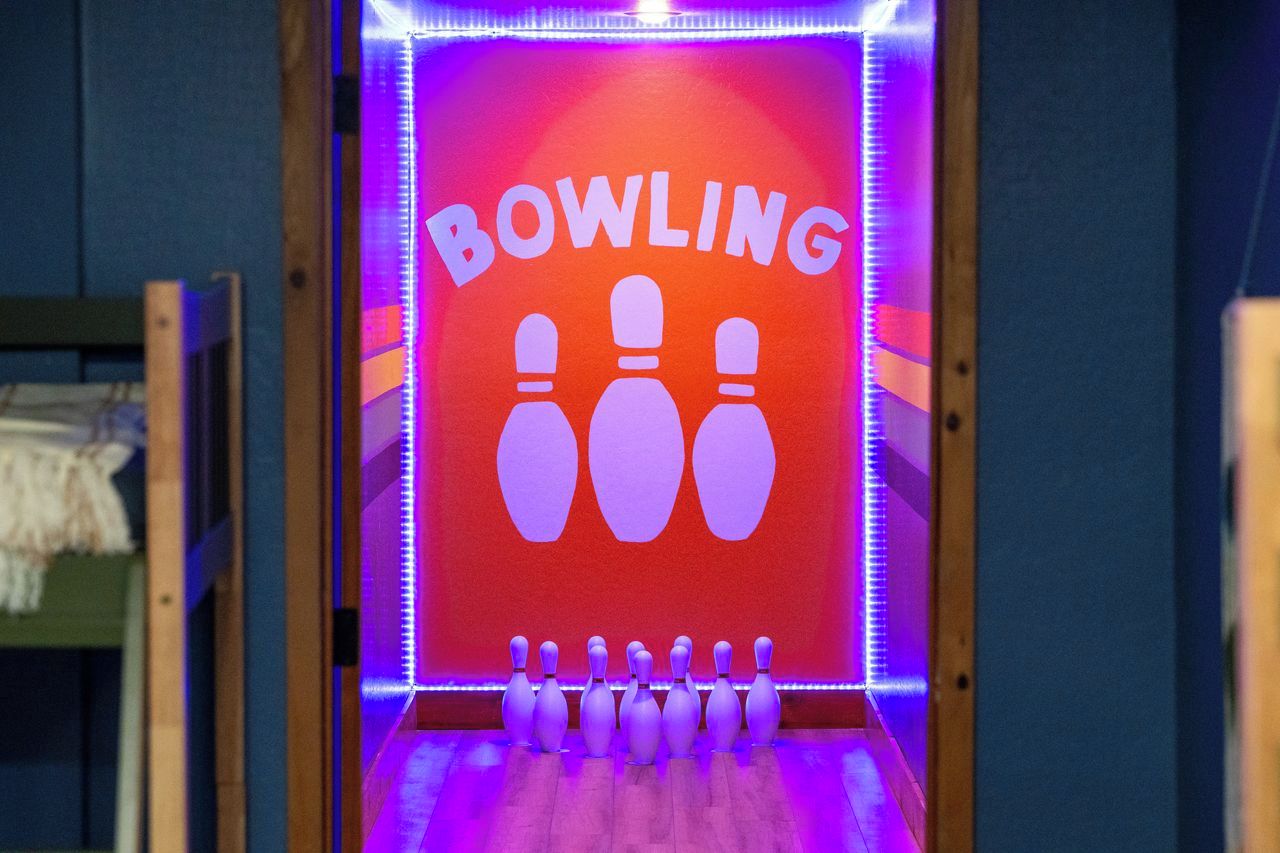 A bowling alley with a neon sign that reads "BOWLING" and multiple bowling pins arranged in a row.